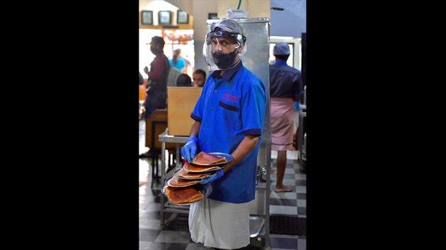 A waiter wearing a face shield and a mask poses for a photograph while serving food at a restaurant in Bengaluru. The reopening of public spaces comes as India’s tally of the coronavirus disease (Covid-19 ) has risen and it is now the fifth most-affected country in the world. India’s count rose to 246,628 on June 7 after 9,971 cases were reported in 24 hours, the highest single-day rise yet, reported HT. (Manjunath Kiran / AFP) 