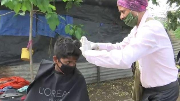 Ravindra Birari giving a haircut to a child. (ANI) Ravindra Birari giving a haircut to a child. (ANI)