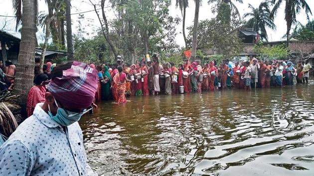 In Harinhula village, local residents line up for relief material as water levels rise due to the full-moon tide .
