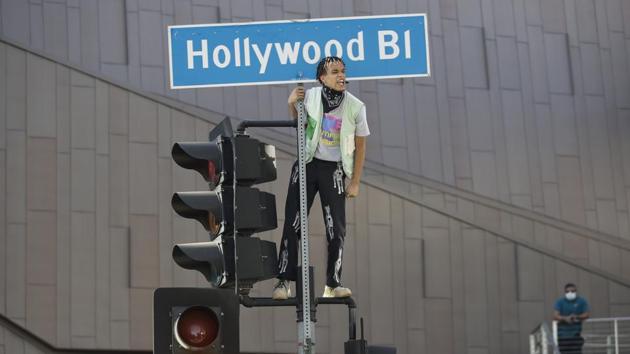 A demonstrator shouts slogans after climbing on a traffic light on June 7 in the Hollywood area of Los Angeles, during a protest over the death of George Floyd. While the mayor oversees the police, the city council has authority over the budget and policy. (Marcio Jose Sanchez / AP)