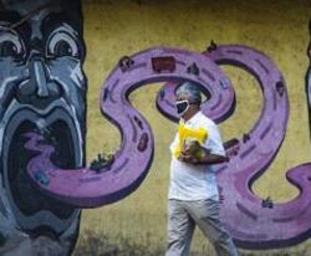 A man walks past a wall graffiti as he wears a protective mask in Pune.(Pratham Gokhale/HT Photo)