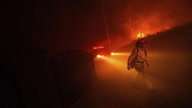A firefighter walks past the beams of an emergency vehicle while the Quail Fire burns on June 6. With 600 personnel deployed, firefighting efforts appeared to be gaining ground and CAL Fire registered a 40% containment rate on June 8. (Noah Berger / AP)