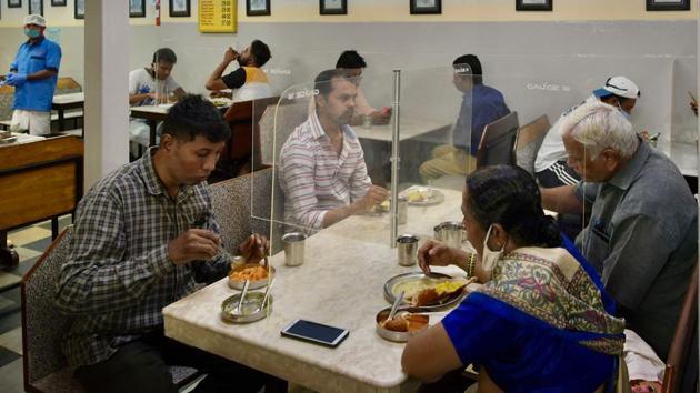 Customers eat their meals at tables divided with transparent panels in a restaurant in Bengaluru.  (Manjunath Kiran / AFP) 
