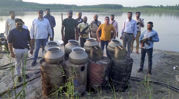 File photo of the anti smuggling wing of the police destroying illicit country made liquor near Sutlej river in Ludhiana in June this year.(HT Photo)