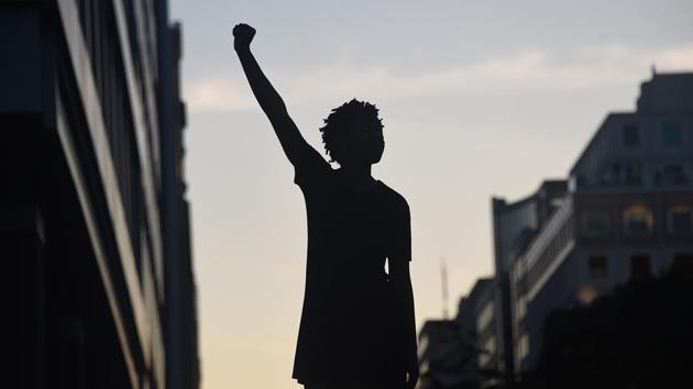 A demonstrator's silhouette is seen as they raise a fist during a protest against police brutality and the death of George Floyd, near the White House on June 7 in Washington, DC. Floyd died on May 25 after a white officer pressed his knee into Floyd’s neck, ignoring his “I can’t breathe” cries. A majority of the members of the Minneapolis City Council said on June 7 that they support disbanding the city’s police department. (Oliver Douliery / AFP)