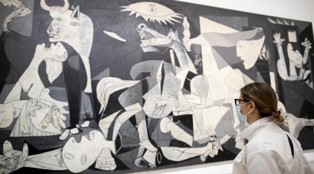 A visitor looks at Pablo Picasso's painting 'Guernica' as the Reina Sofia museum reopened to the public in Madrid, Spain, Saturday, June 6, 2020. Madrid's Museo del Prado opened its doors on Saturday for 1,800 visitors, after its closing during the coronavirus pandemic. The visitors were required to wear face masks and have their temperature taken before taking in what the museum called its "most iconic works". (AP Photo/Manu Fernandez)(AP)