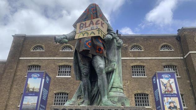 The statue of Robert Milligan, a noted West Indian merchant, slaveholder and founder of London's West India Docks, stands covered in a sack-cloth and sign reading Black Lives Matter, outside the Museum of London Docklands on June 9. By taking matters into their own hands, the protesters raised the temperature of a debate that had previously remained confined to the realms of marches, petitions and newspaper columns. (Renee Bailey/PA via AP)