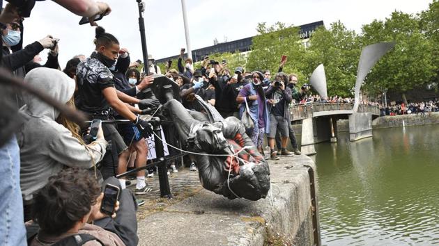 Protesters throw a statue of slave trader Edward Colston into Bristol harbour during a Black Lives Matter protest rally in Bristol, England on June 7. The statue of Edward Colston, who made a fortune in the 17th century from trading in West African slaves, was torn down by a group of demonstrators taking part in a worldwide wave of protests. (Ben Birchall/PA via AP)