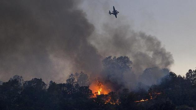 Air tankers from throughout the state were pressed into action to dump aerial retardant as firefighters worked on the ground lighting backfires as a containment strategy, hindering the path of the wildfire and mopping up hot spots through the weekend. (Noah Berger / AP)