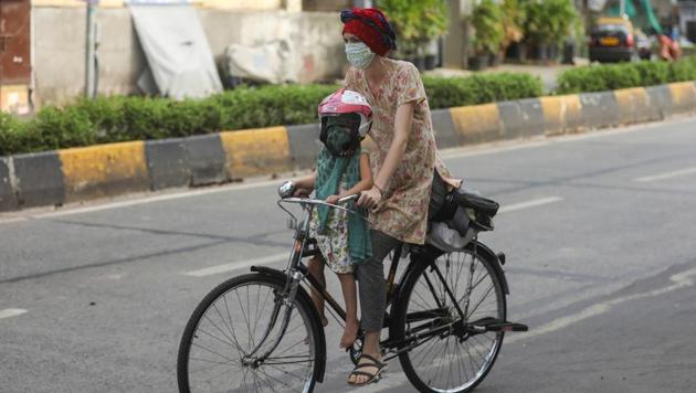 A woman rides a bicycle carrying a child after some restrictions were lifted during a nationwide lockdown to slow the spread of the coronavirus disease in Mumbai on June 8, 2020.(Reuters File Photo)