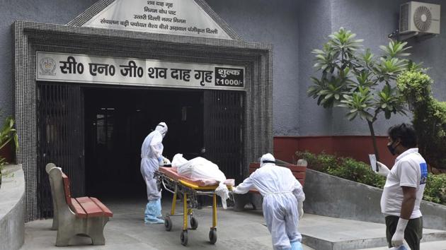 Health workers in PPE coveralls during the funeral rites of a person who died of Covid-19 at Nigambodh Ghat crematorium in New Delhi(Sonu Mehta/HT PHOTO)