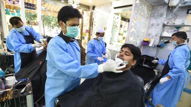 Hairdressers clad in protective coveralls and gloves seen at work in a salon in Gandhi Market on June 5. With the reopening of economic activities that have resulted in public gatherings, the anxiety of higher infection rates has risen as well. (Arvind Yadav/HT Photo)