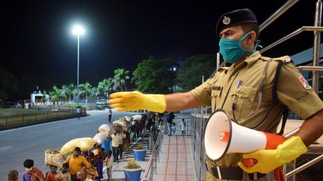 A police constable announces to maintain social distancing as migrants from Chhattisgarh arrive to board a special train to reach their native places at a railway station, during the ongoing COVID-19 lockdown, in Prayagraj.(PTI)