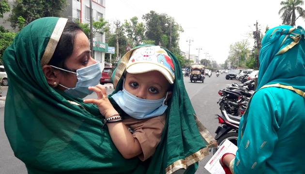 A woman tries to save her child from heat as well as Covid pandemic at Rohtak on Tuesday. (Manoj Dhaka/HT) A woman tries to save her child from heat as well as Covid pandemic at Rohtak on Tuesday. (Manoj Dhaka/HT)