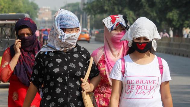 Women use scarves to protect themselves from the scorching sun as they walk along a road on a hot summer day.(PTI photo)