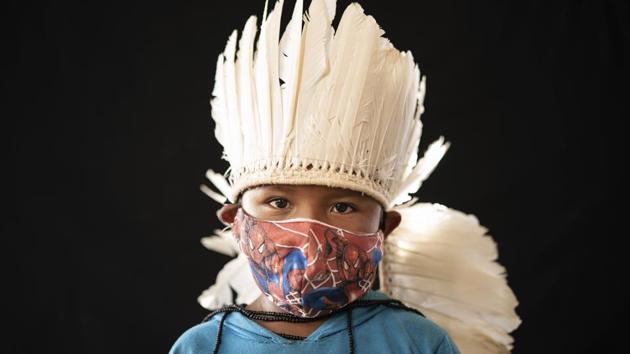 Six-year-old Ezinaldo dos Santos, of the Sateré Mawé indigenous ethnic group, poses for a portrait wearing the traditional dress of his tribe and a face mask amid the spread of the new coronavirus in the Gaviao community near Manaus, Brazil, Friday, May 29, 2020. (AP Photo/Felipe Dana) (AP) Six-year-old Ezinaldo dos Santos, of the Sateré Mawé indigenous ethnic group, poses for a portrait wearing the traditional dress of his tribe and a face mask amid the spread of the new coronavirus in the Gaviao community near Manaus, Brazil, Friday, May 29, 2020. (AP Photo/Felipe Dana) (AP)