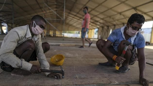 Workers lay flooring panels during the construction of a 1000 bed non-critical hospital for Covid-19 treatment at the Bandra Kurla Complex exhibition ground in Mumbai.(Bloomberg)