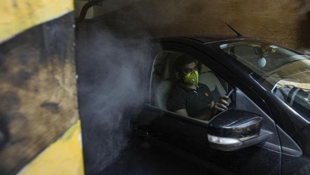 A disinfectant spray installed in the parking lot of a shopping mall is activated by a passing car in New Delhi on June 7. Squirts of sanitizer through the day, fumigants and clouds of disinfectant mist drive home the need for personal hygiene. (Biplov Bhuyan / HT Photo)