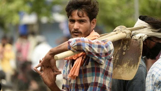 A daily wage worker holding his shovel waits for work at Labor chowk on Khandsa road, in Gurugram on Thursday.(Parveen Kumar/HT Photo)