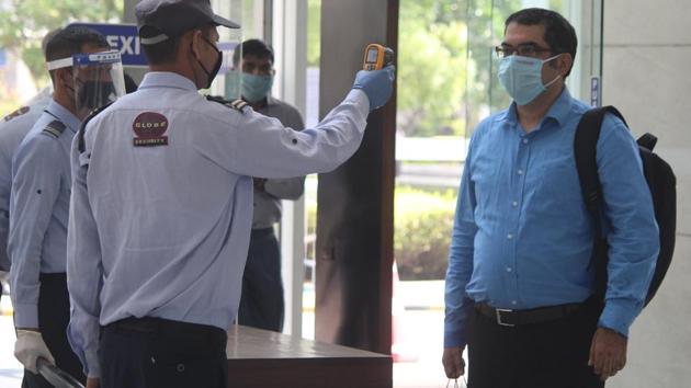 A security guard thermal screens people as they enter an office building in Gurugram on June 8. Beyond our homes, the beep of an infrared thermometer now grants or withholds access to any public space or experience. (Yogendra Kumar / HT Photo)