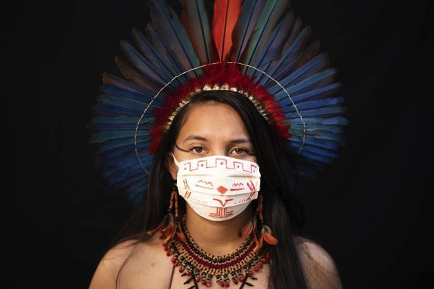 Samela, 23, of the Sateré Mawé indigenous ethnic group, poses for a portrait wearing the traditional dress of her tribe and a face mask amid the spread of the new coronavirus in Manaus, Brazil, Wednesday, May 27, 2020. Samela, whose mother Sonia Vilacio recovered from symptoms consistent with COVID-19 using natural remedies at home, is the first member of her family to attend university, where she studies biology. (AP Photo/Felipe Dana) (AP) Samela, 23, of the Sateré Mawé indigenous ethnic group, poses for a portrait wearing the traditional dress of her tribe and a face mask amid the spread of the new coronavirus in Manaus, Brazil, Wednesday, May 27, 2020. Samela, whose mother Sonia Vilacio recovered from symptoms consistent with COVID-19 using natural remedies at home, is the first member of her family to attend university, where she studies biology. (AP Photo/Felipe Dana) (AP)