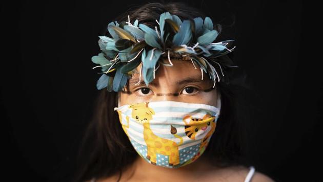 Iasmin, 8, of the Sateré Mawé indigenous ethnic group, poses for a portrait wearing the traditional dress of her tribe and a face mask amid the spread of the new coronavirus in Manaus, Brazil, Wednesday, May 27, 2020. (AP Photo/Felipe Dana) (AP) Iasmin, 8, of the Sateré Mawé indigenous ethnic group, poses for a portrait wearing the traditional dress of her tribe and a face mask amid the spread of the new coronavirus in Manaus, Brazil, Wednesday, May 27, 2020. (AP Photo/Felipe Dana) (AP)