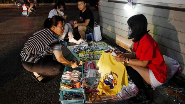 A street vendor sell products to a customer beside a police cabin on the roadside in Beijing on June 10. “The street vendor economy and the small shop economy are important sources of employment... and are just as vital to China as high-end luxury stores,” Li Keqiang told traders during a visit to northeast China last week, after asking how they had fared during months of restrictions due to the coronavirus. (GREG BAKER / AFP)