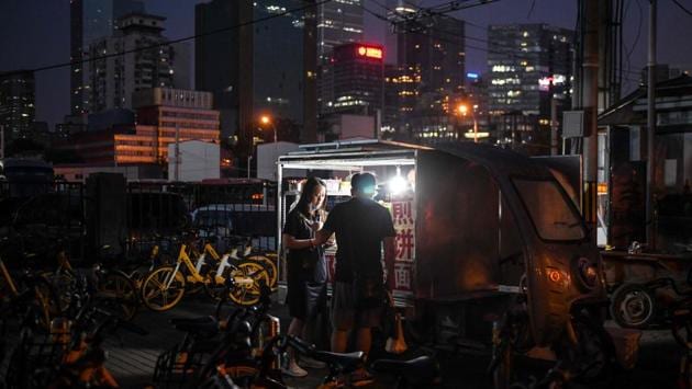 People at a street food vendor’s in Beijing on June 10. Tang Min, former chief economist of the Asian Development Bank’s mission in China, told a government-organised press conference on June 11 that street stalls can create some new employment but “cannot replace the formal economy.” But no country would allow “street stalls everywhere, with disorder everywhere,” he added. (GREG BAKER / AFP)