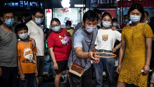 A man plays a ring-toss game at an outdoor market in Wuhan on June 10. People’s Daily, a Communist Party mouthpiece, called for stricter oversight of street traders, while the state-run Beijing Daily claimed that the stalls were backward and “not suited” to the city, AFP reported. (AFP)