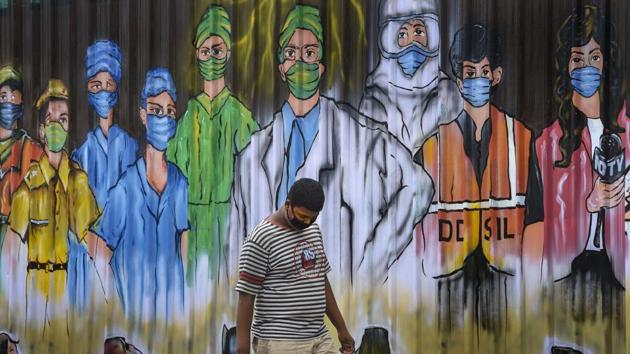 A youth walks past a mural honouring the warriors of Covid-19 in Nizamuddin, New Delhi on Wednesday.(PTI File Photo)