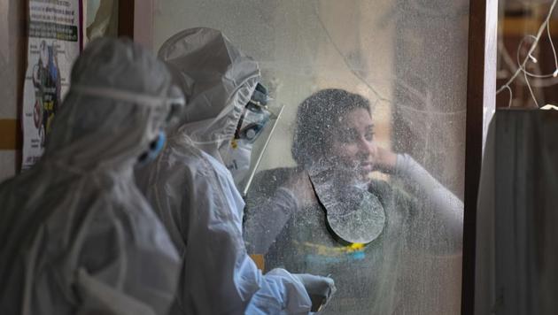 Health workers wearing Personal Protective Equipment (PPE) bodysuits handle a sample at a swab collection booth for Covid-19 testing at a centre in Patel Nagar, New Delhi on Thursday. (Sanchit Khanna/HT PHOTO) Health workers wearing Personal Protective Equipment (PPE) bodysuits handle a sample at a swab collection booth for Covid-19 testing at a centre in Patel Nagar, New Delhi on Thursday. (Sanchit Khanna/HT PHOTO)