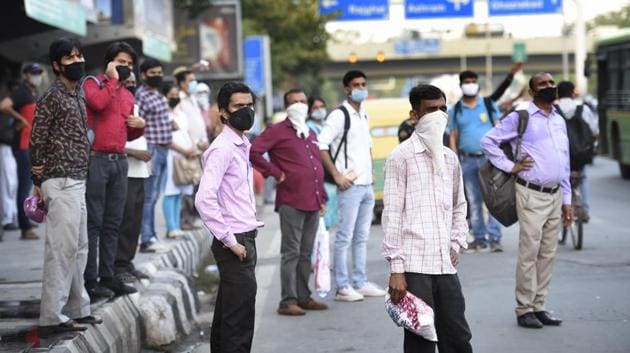 Commuters wear face masks as they wait to board a bus at ITO, in New Delhi on Thursday.(Arvind Yadav/HT Photo)