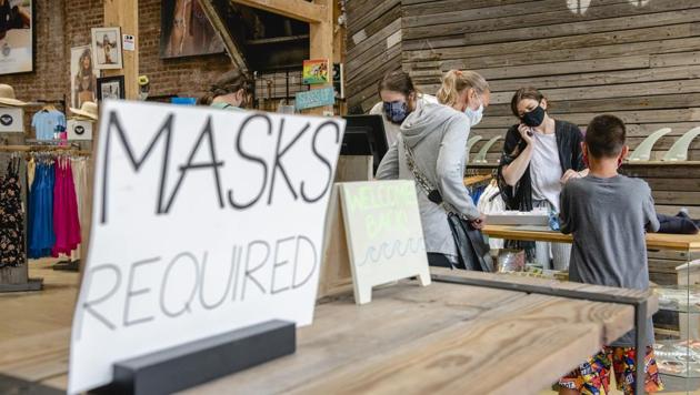 Shoppers wearing protective masks pay at a store in Long Beach, New York, US on Thursday. (Bloomberg Photo) Shoppers wearing protective masks pay at a store in Long Beach, New York, US on Thursday. (Bloomberg Photo)