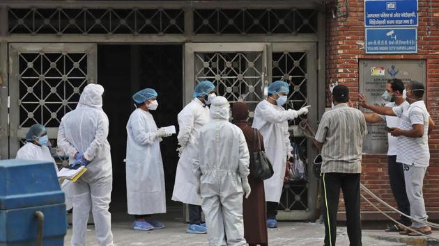 Health workers talk to attendants of a patient at a hospital meant for treating Covid-19 patients in New Delhi, India. (AP) Health workers talk to attendants of a patient at a hospital meant for treating Covid-19 patients in New Delhi, India. (AP)