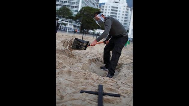 An activist of the NGO Rio de Paz wearing a face shield digs a grave on Copacabana beach. Brazil has become a major epicentre of the coronavirus pandemic, with 41,901 deaths and over 829,900 confirmed cases as of June 12, according to coronavirus tracking website Worldometer. (Pilar Olivares / REUTERS) An activist of the NGO Rio de Paz wearing a face shield digs a grave on Copacabana beach. Brazil has become a major epicentre of the coronavirus pandemic, with 41,901 deaths and over 829,900 confirmed cases as of June 12, according to coronavirus tracking website Worldometer. (Pilar Olivares / REUTERS)
