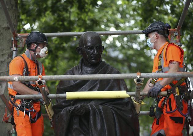 Workers put up a protective screen around the statue of Mahatma Gandhi in Parliament Square ahead of expected rival demonstrations by anti-racism and far-right protesters in London, Friday, June 12, 2020.(AP)