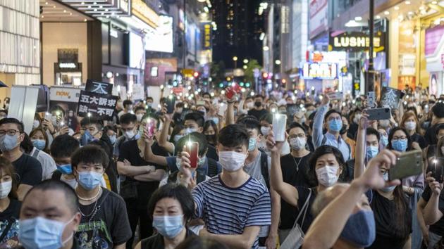 Demonstrators wearing protective masks shine lights from their smartphones during a protest in the Causeway Bay district of Hong Kong, China on Friday.(Bloomberg)