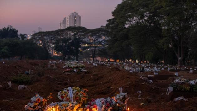 Flowers and candles lay on the grave of a Covid-19 victim at the Vila Formosa cemetery in Sao Paulo, Brazil. (Bloomberg) Flowers and candles lay on the grave of a Covid-19 victim at the Vila Formosa cemetery in Sao Paulo, Brazil. (Bloomberg)