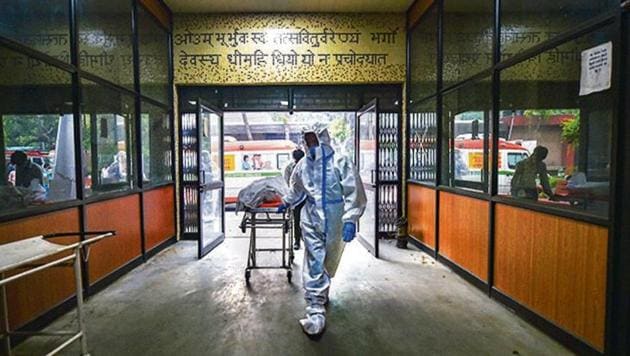 A health worker carries the body of a patient, who succumbed to the coronavirus disease, for cremation in New Delhi on Saturday.(PTI Photo)