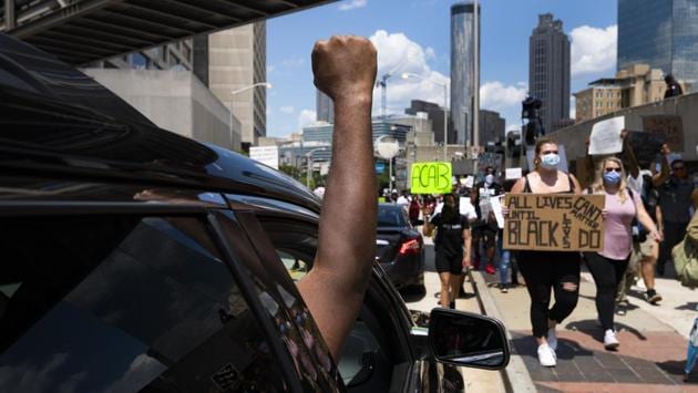 Protesters get support from a passenger in a car as they march past CNN during a demonstration over police brutality and racism on June 13 in Atlanta. Atlanta Police Chief Erika Shields stepped down yesterday responding to demonstrators’ call for action in response to the killing of 27-year-old Rayshard Brooks. (John Amis / Atlanta Journal-Constitution via AP) Protesters get support from a passenger in a car as they march past CNN during a demonstration over police brutality and racism on June 13 in Atlanta. Atlanta Police Chief Erika Shields stepped down yesterday responding to demonstrators’ call for action in response to the killing of 27-year-old Rayshard Brooks. (John Amis / Atlanta Journal-Constitution via AP)