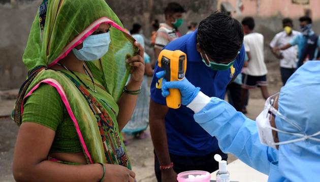 A health care worker checks the temperature in the Dharavi slum area during nationwide lockdown to control the spread of the coronavirus in Mumbai on Saturday.(Satish Bate/HT Photo)