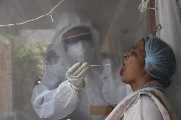 A health worker takes a swab sample from a woman at a mobile Covid-19 testing van, New Delhi, June 12, 2020(Vipin Kumar/HT PHOTO)