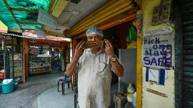A man wears a mask stitched by Laxmi Das (unseen) near a free mask dispenser, during the ongoing Covid-19 nationwide lockdown in New Delhi on Saturday. (PTI Photo) A man wears a mask stitched by Laxmi Das (unseen) near a free mask dispenser, during the ongoing Covid-19 nationwide lockdown in New Delhi on Saturday. (PTI Photo)