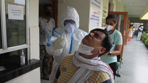 A doctor in PPE coveralls collects swab sample from people for coronavirus testing, during lockdown at Primary Health Centre (PHC) Wazirabad in Gurugram on Saturday. (Yogendra Kumar/HT Photo)