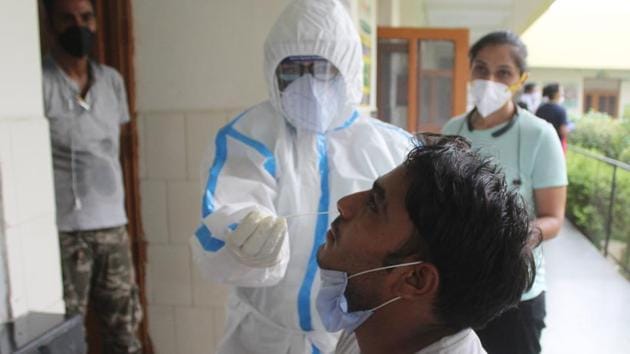 A doctor in PPE coveralls collects swab sample from people for coronavirus testing during lockdown. (Yogendra Kumar/HT PHOTO) A doctor in PPE coveralls collects swab sample from people for coronavirus testing during lockdown. (Yogendra Kumar/HT PHOTO)