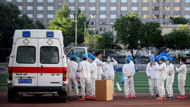 Medical professionals wearing protective suits gather at the Guang’an Sport Centre before a mass swab test for people who visited or live near Xinfadi market . A complex of warehouses and trading halls, Xinfadi is more than 20 times larger than the seafood market in the city of Wuhan, where the outbreak was first identified. (Noel Celis / AFP)