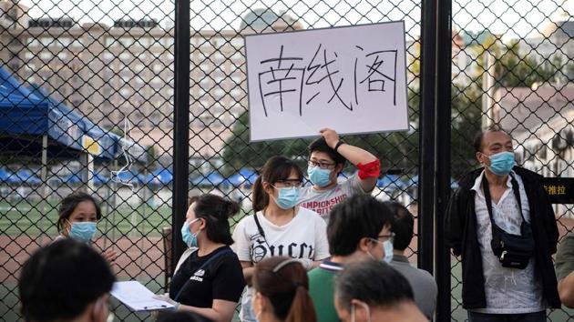 A man holds a placard as people who visited or live near Xinfadi market queue for a swab test at Guang’an Sport Centre. Beijing began mass testing on June 14, with tens of thousands of checks. Results from the first 6,075 were negative, Gao Xiaojun from the Beijing public health commission told Reuters. (Noel Celis / AFP)