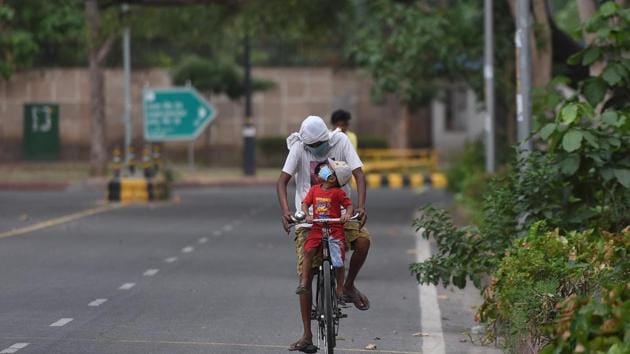 A cyclist travelling with a child at Connaught Place in New Delhi.(Sonu Mehta/HT PHOTO)