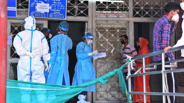 Medical workers speak with family members of people admitted with coronavirus infections, outside the Covid-19 ward at Lok Nayak Jai Prakash Narayan Hospital in New Delhi on Sunday.(Raj K Raj/HT Photo)