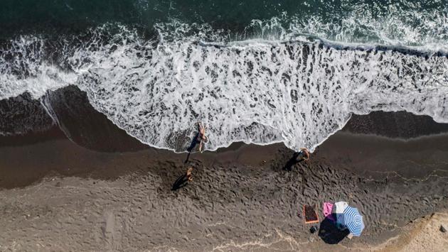 People enjoy the sea and the sun at a beach in Santorini on June 14. According to an AP report, the most recent official figures from June 14 show no daily coronavirus deaths in Greece for five days, with the total at 183 in this country of nearly 11 million people. Confirmed cases stand at 3,121. (Aris Messinis / AFP)